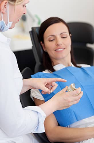 Dentist Explaining Teeth Model To Female Patient — Pain Free Dental Clinic In Moss Vale, NSW