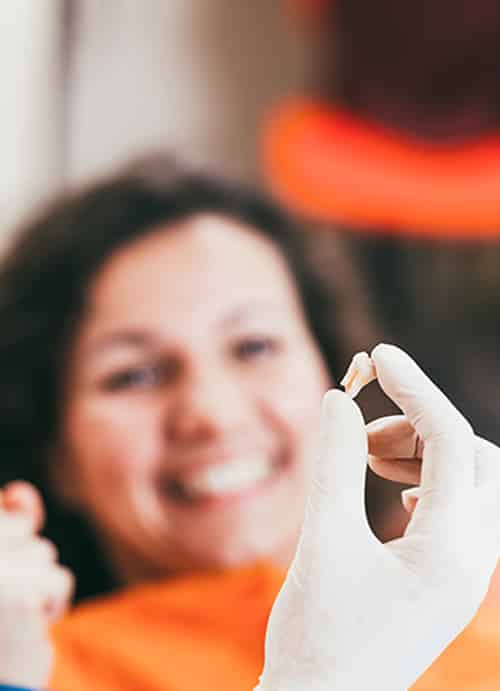 Happy Patient Looking At Their Extracted Tooth — Pain Free Dental Clinic In Moss Vale, NSW